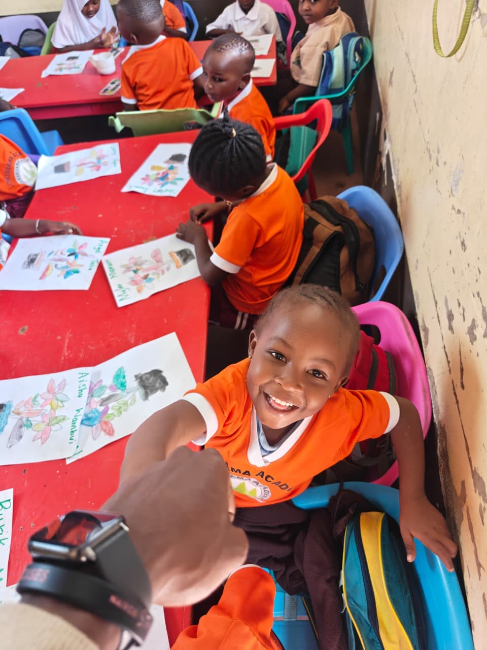 A pre-primary learner smiling during a colouring lesson